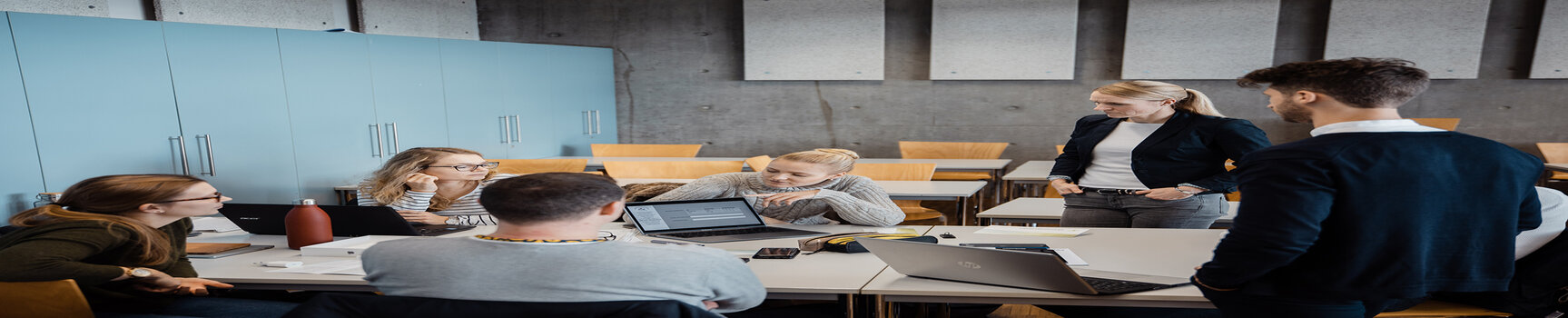 Vorlesungssituation: Dozierender und Studierende im Gespräch in Kleingruppe