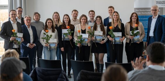 Eine Gruppe von Personen positioniert sich auf einer Bühne.