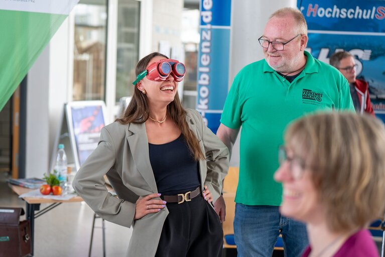 Eine Frau hat eine Rauschbrille der Verkehrswacht auf. Ein Mann steht daneben, eine weitere Frau ist von der Seite zu sehen. 