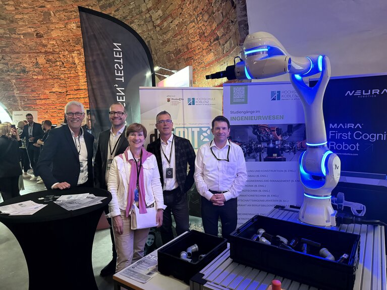 Eine Gruppe von vier Männern und einer Frau auf der Messe mit einem Roboter