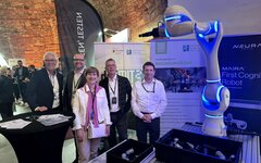 Eine Gruppe von vier Männern und einer Frau auf der Messe mit einem Roboter