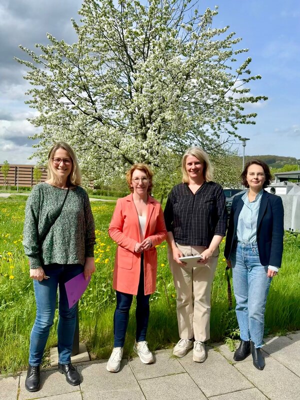 Vier Frauen stehen auf dem Gelände des Campus Remagen der Hochschule Koblenz vor einem blühenden Baum